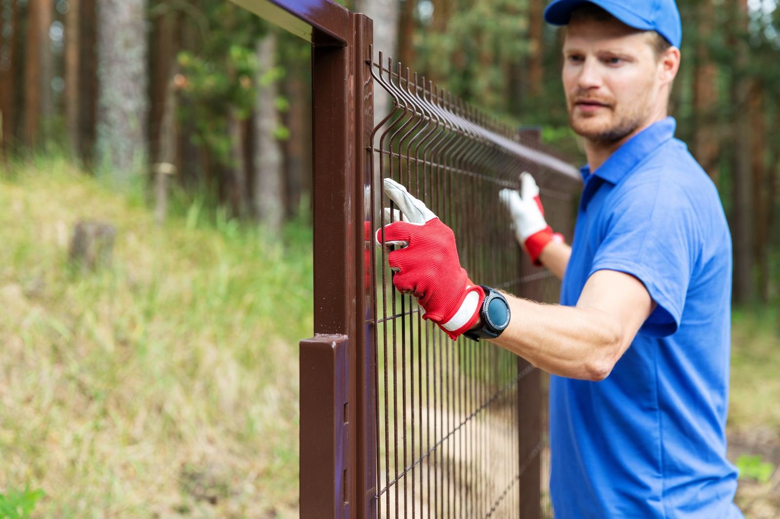 Worker installing a welded mesh fence panel